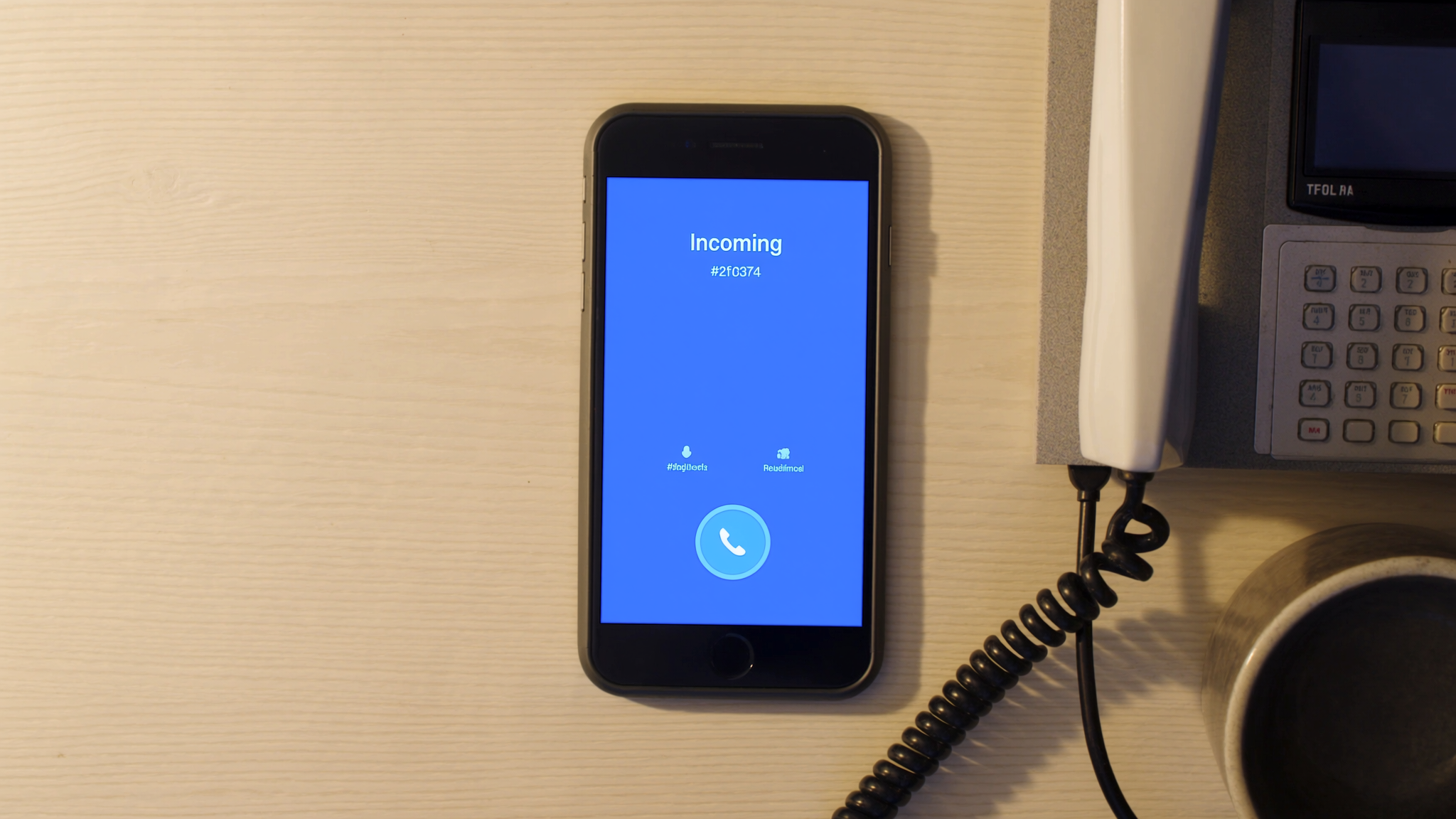 A smartphone on a wooden desk showing an incoming-call interface with the call button glowing in brand blue, beside a vintage corded desk phone with the receiver lifted